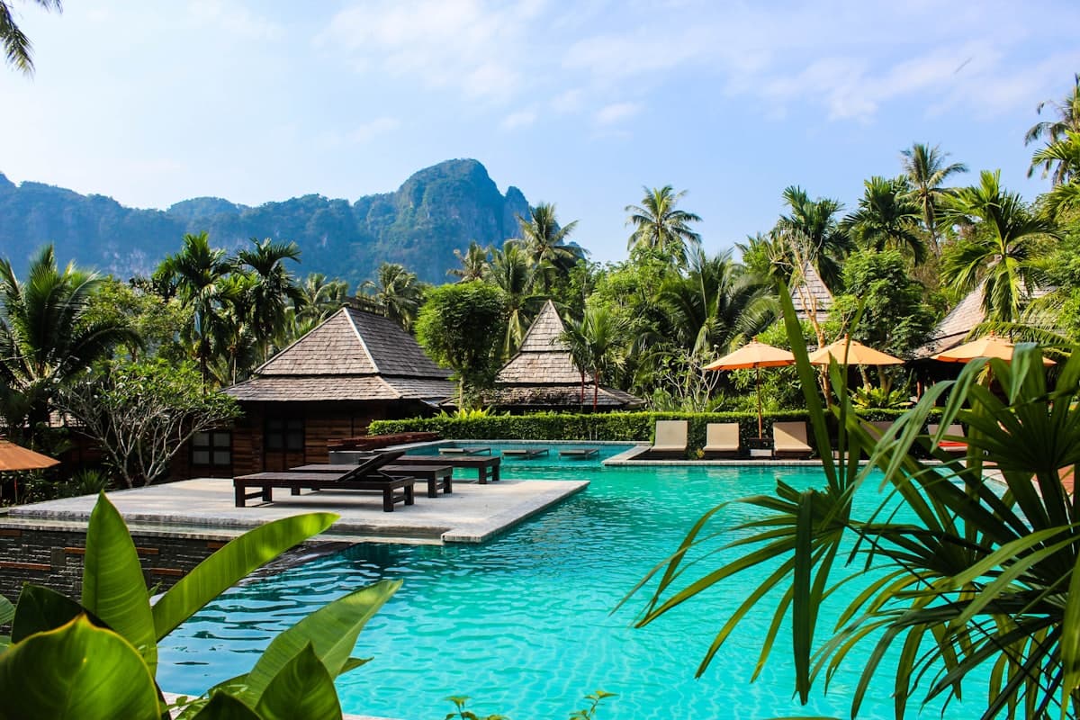 Thatched villas around a resort pool fringed with tropical planting