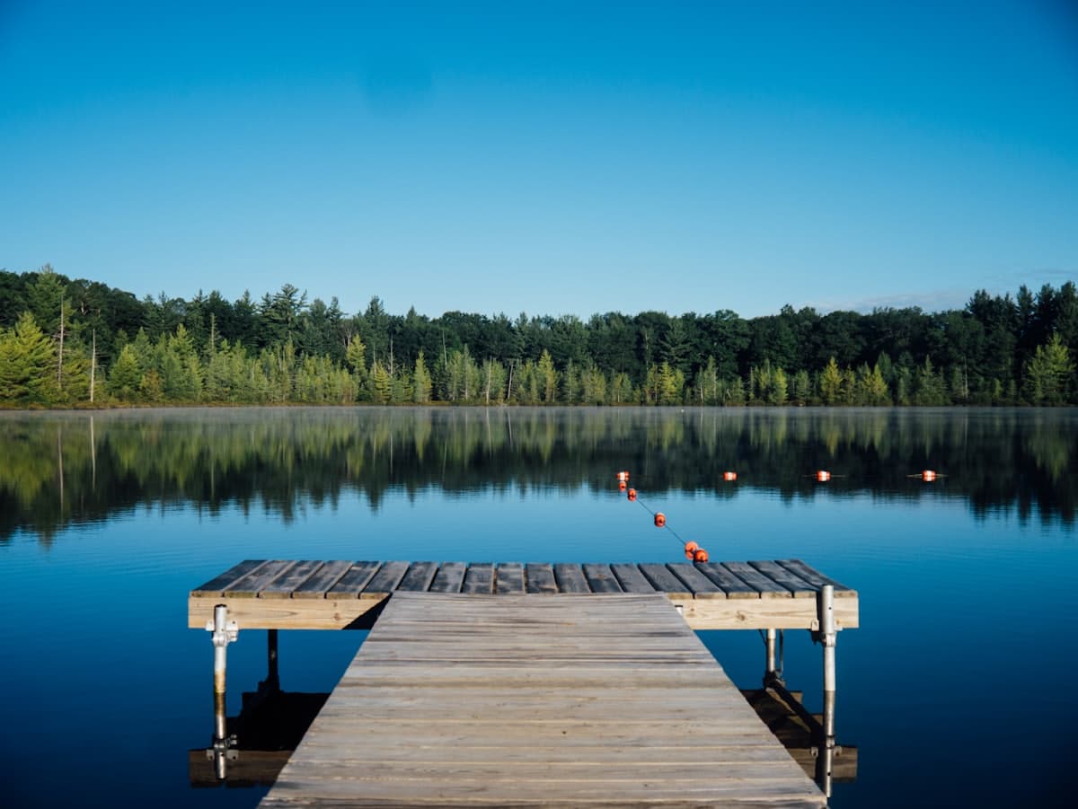 Wooden jetty reaching out over calm water at dusk
